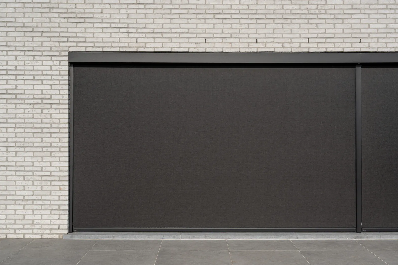 Screen met zichtbare kast en volledig neergelaten doek op een witte gevel